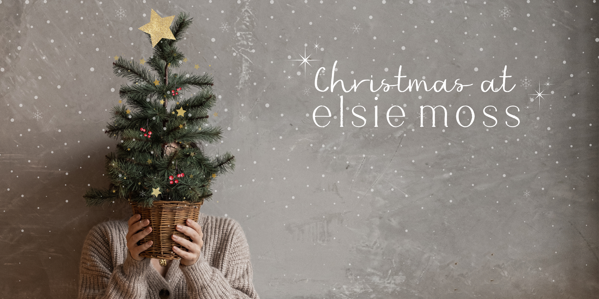 Person holding a small decorated Christmas tree with 'Christmas at elsie moss' text on a gray background