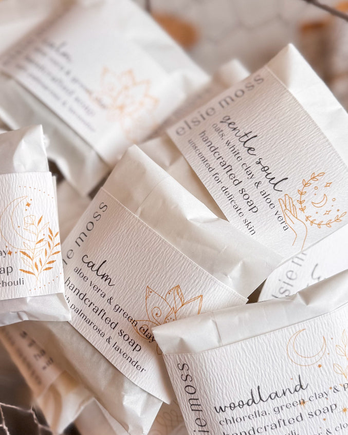 Handcrafted soap packages with visible branding on a textured surface