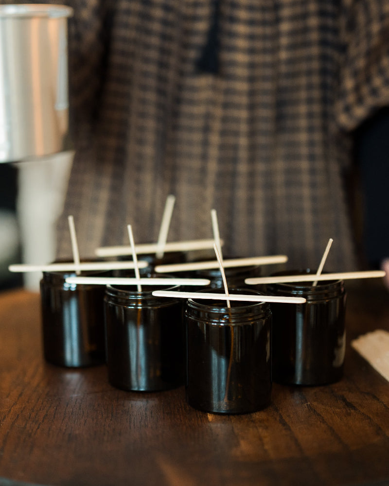 Black containers with lit candles on wooden surface