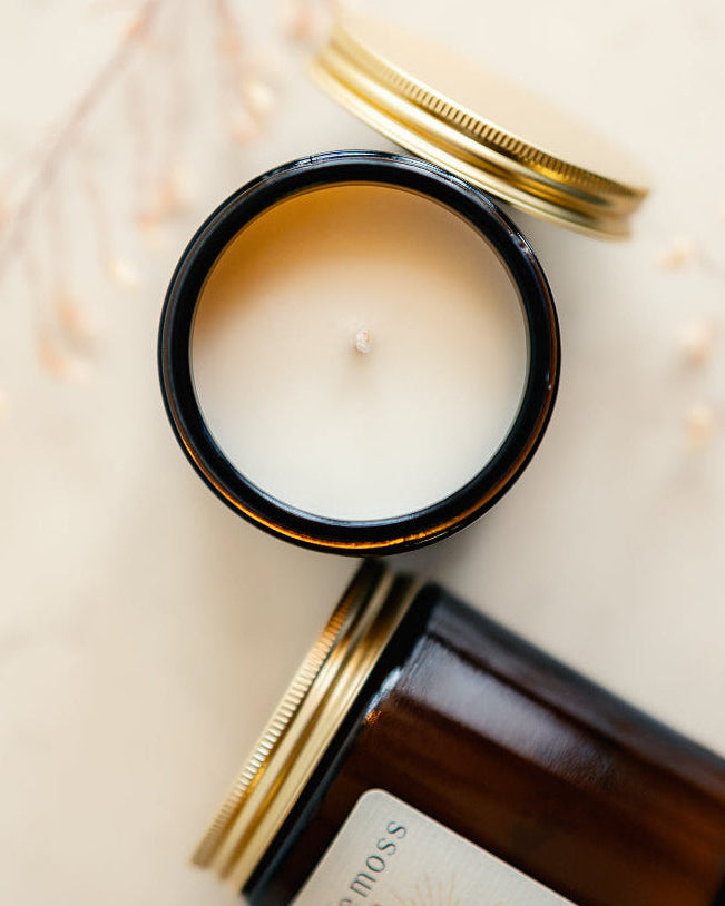 Two candles, one lit and one unlit, on a textured surface with a soft focus background.