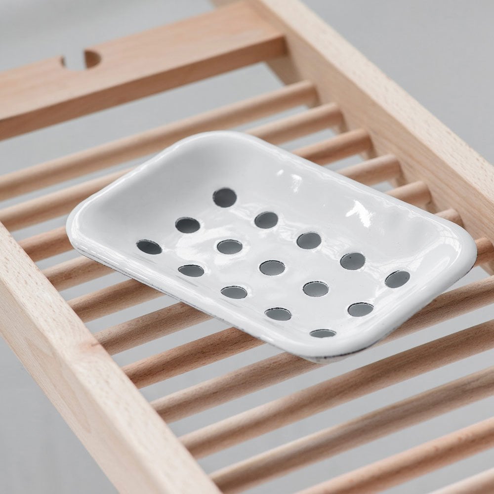 White enamel soap dish with drainage holes on a wooden rack