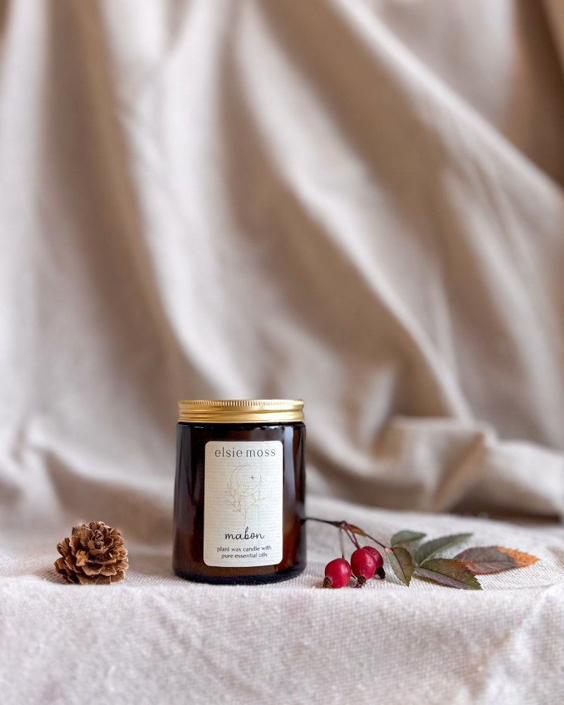 A dark amber glass jar candle with a gold lid and a cream label reading &