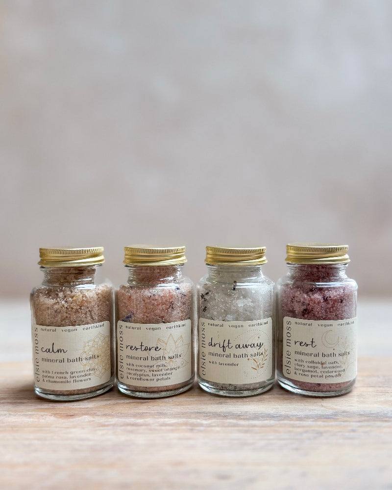Four jars of bath salts with labels on a wooden surface
