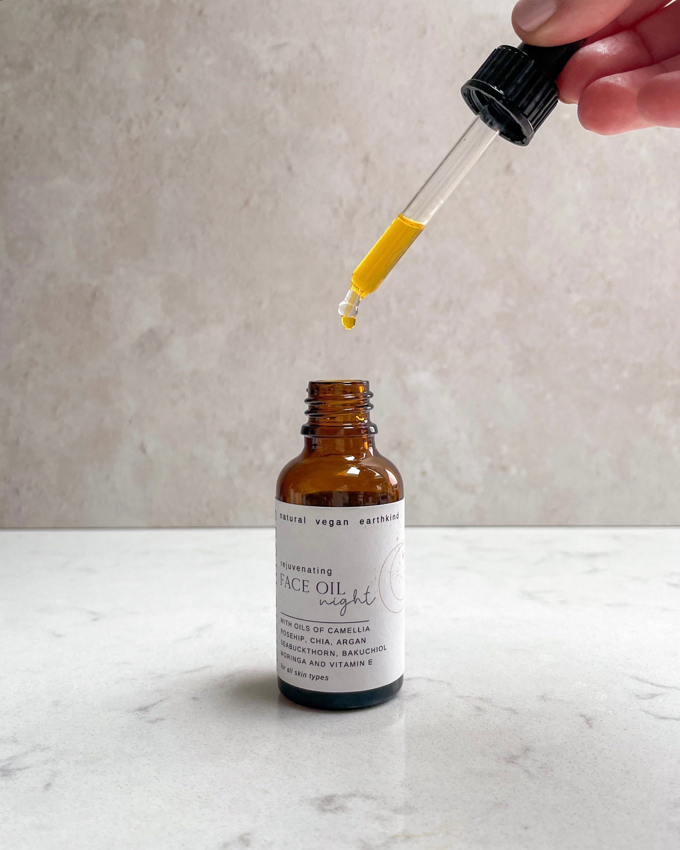 Bottle of face oil with a dropper on a marble surface