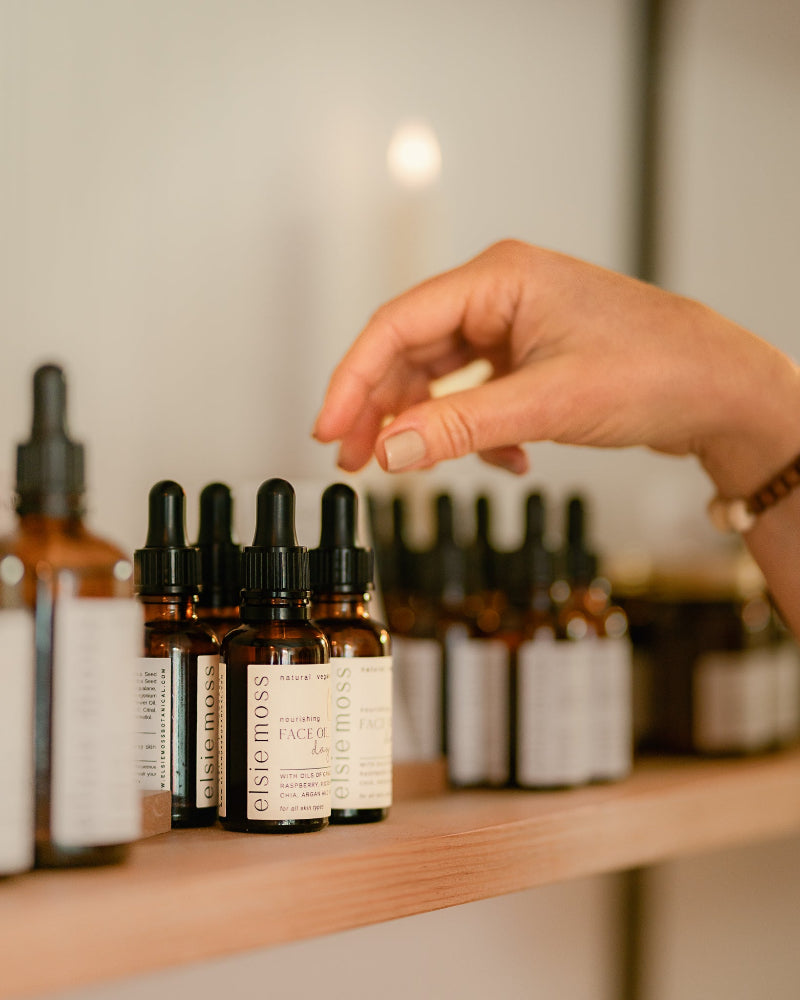 Hand reaching for a bottle on a shelf with skincare products