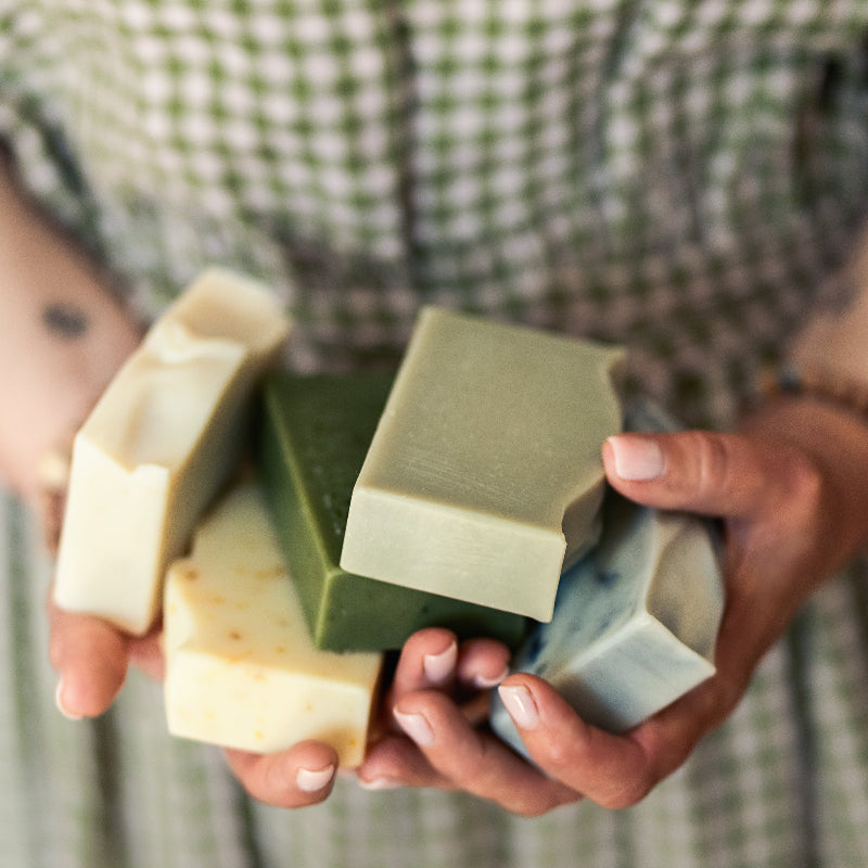 Person holding four bars of soap in their hands