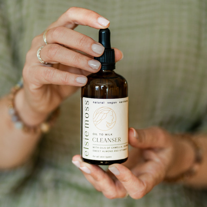 Person holding a bottle of Ciste Mois cleanser with a blurred green background