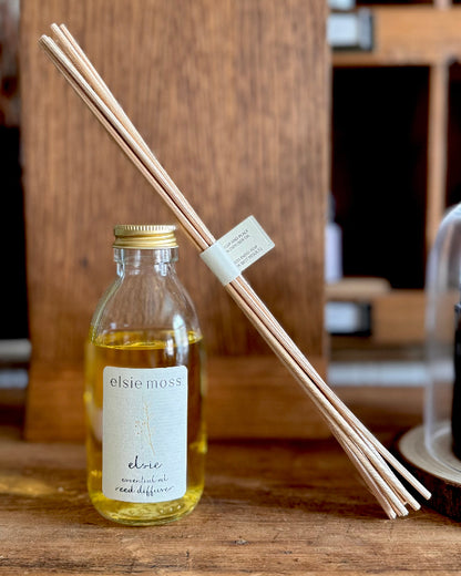 Reed diffuser with bottle and sticks on a wooden surface