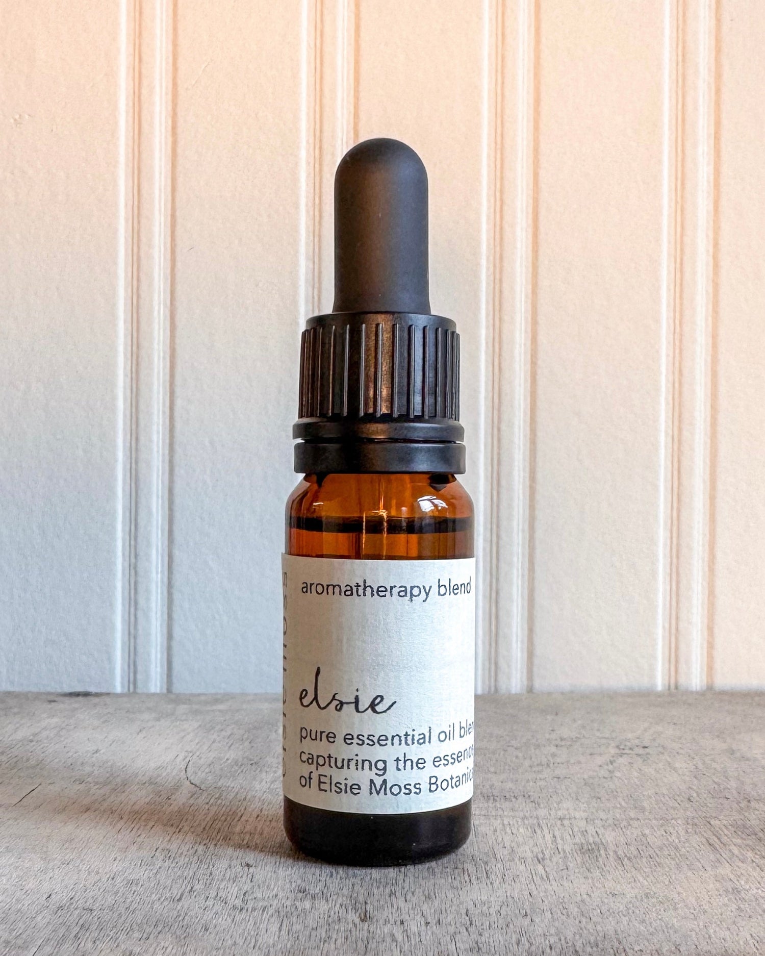 Bottle of Elsie essential oil blend on a wooden surface with a neutral background