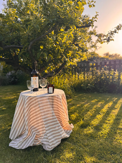 Table with wine bottles and glasses under a tree in a garden setting