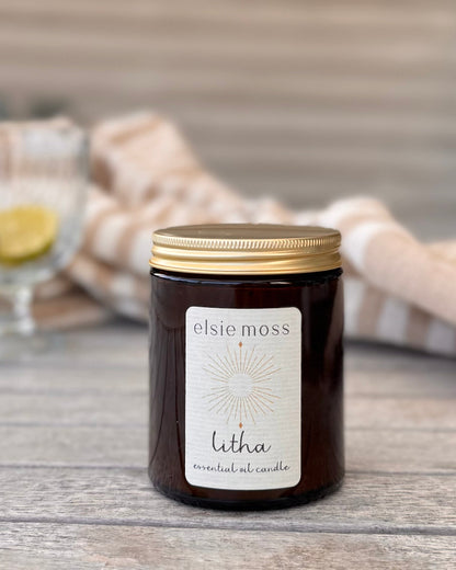 Elsie Moss Litha candle on a wooden surface with a blurred background