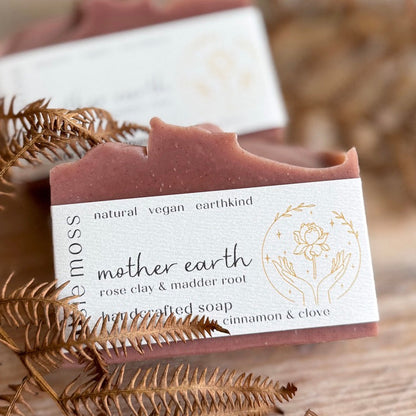 Bar of soap with a label on a wooden surface with dried leaves