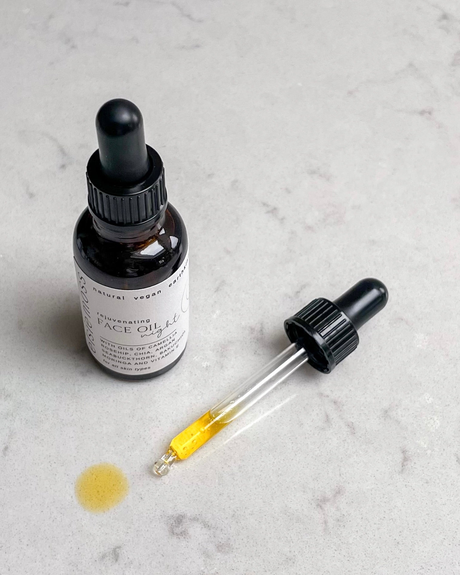 Facial oil dropper with a label on a gray marble surface