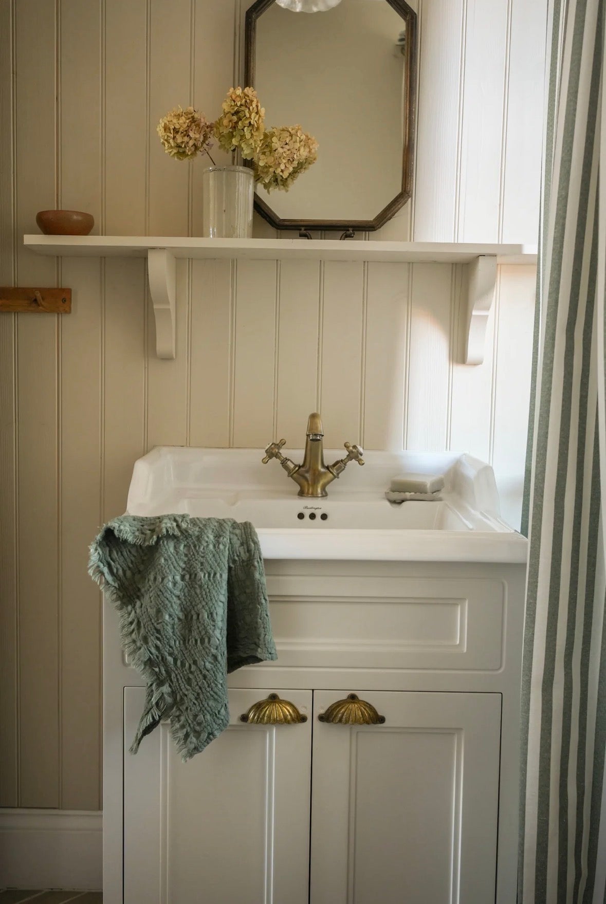 Bathroom vanity with white sink, gold faucet, and green towel.