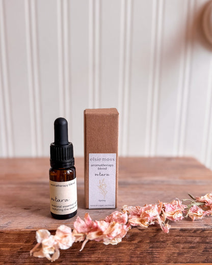 A bottle of elsiemoss product on a wooden surface with dried flowers.