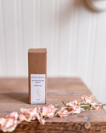 Elsie Moss aromatherapy blend bottle on a wooden surface with flowers