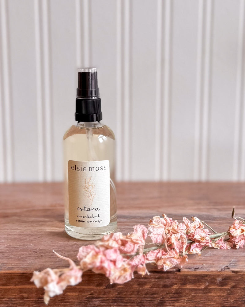 Bottle of elsie moss product on a wooden surface with pink flowers