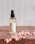 Bottle of elsie moss product on a wooden surface with pink flowers