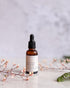Brown glass bottle with dropper on a light surface with floral elements