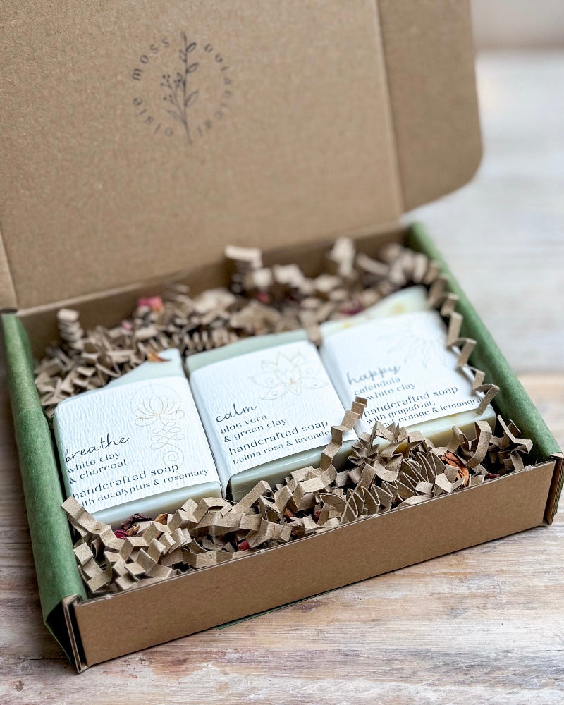 Three soaps in a box with visible branding on a wooden surface