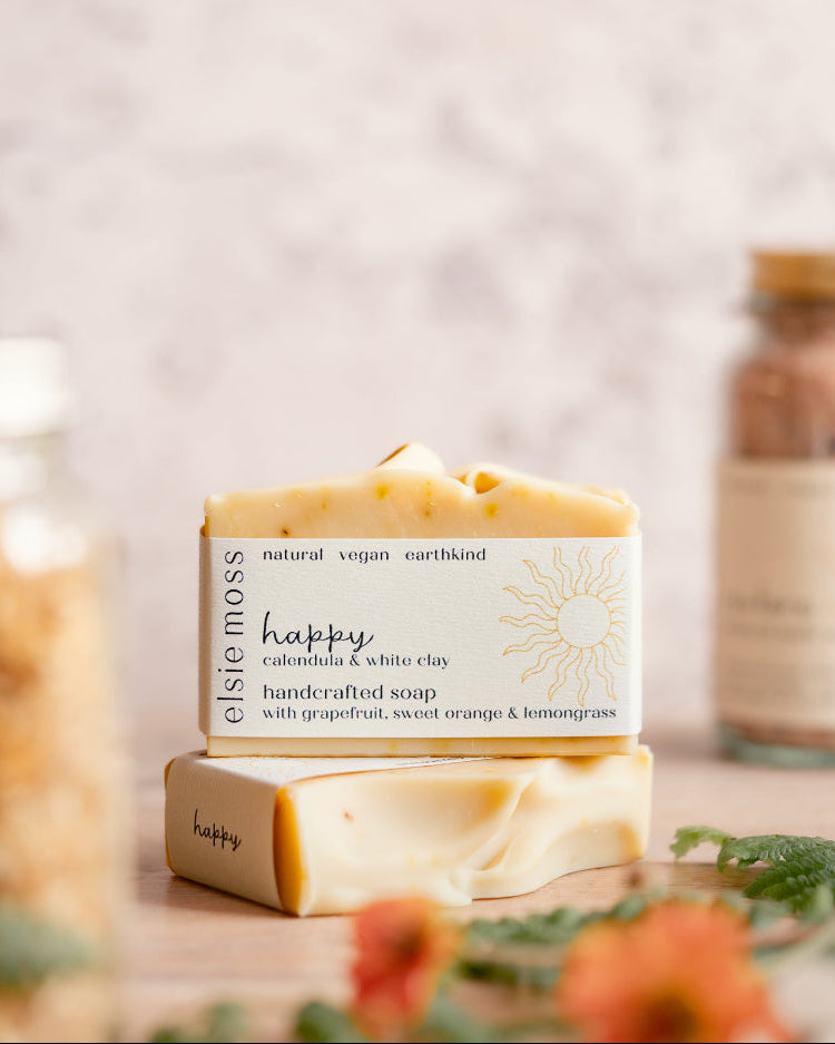 Bar of soap with a visible label on a wooden surface with blurred jars in the background