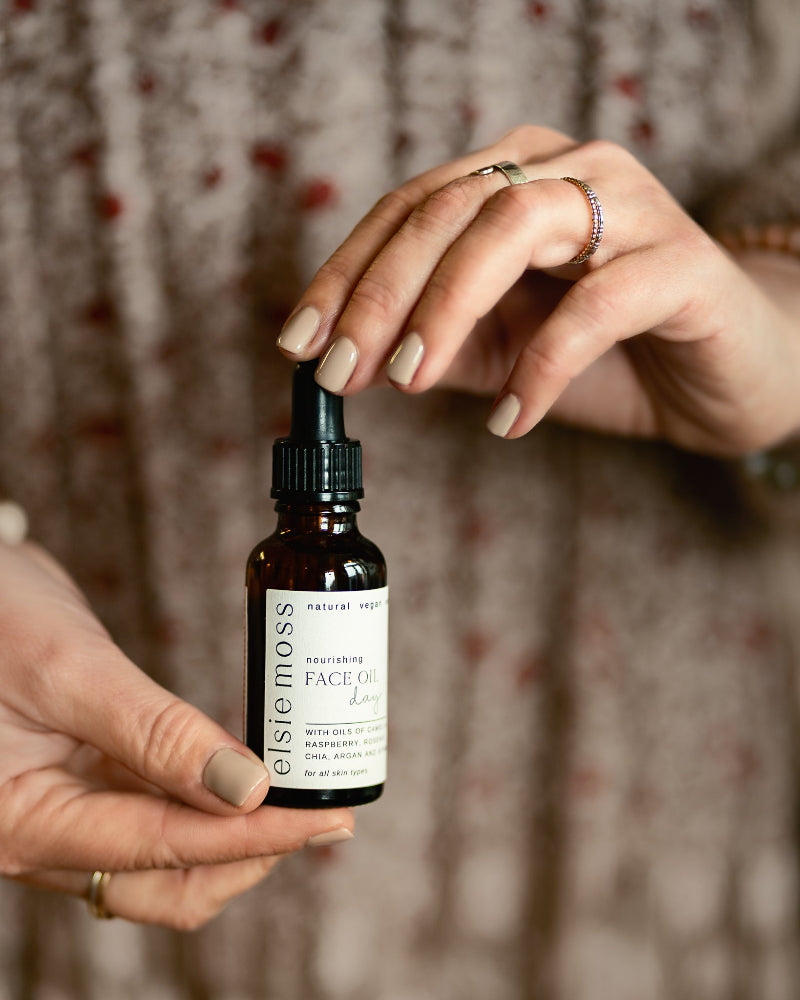 Person holding a bottle of Elsie Moss face oil with a blurred background