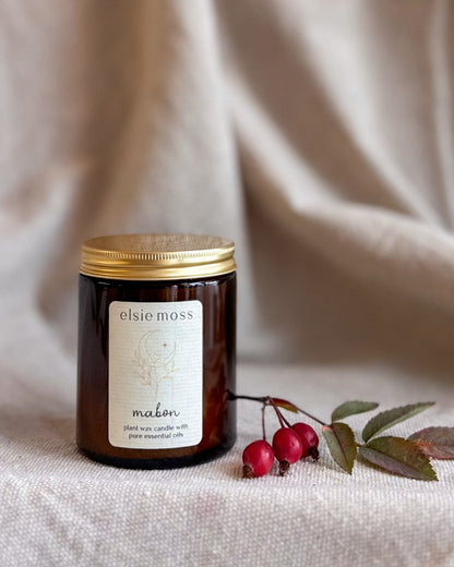 An amber glass jar candle with a gold lid and a cream label reading &