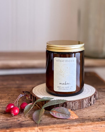 An amber glass jar candle with a gold lid and a cream label reading &