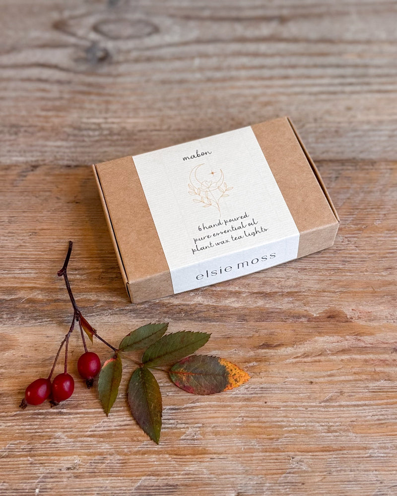 A kraft paper box with a white paper band label sits on a rustic wooden tabletop. The label reads &