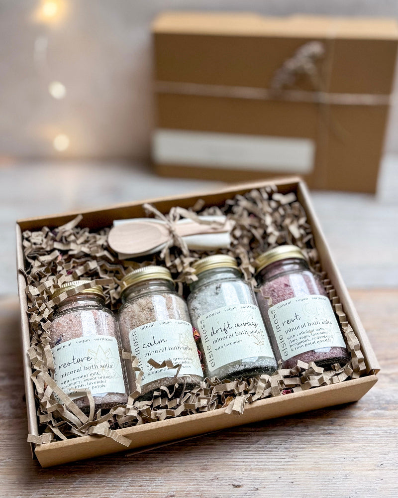 Set of four small jars with labels in a decorative box on a wooden surface.