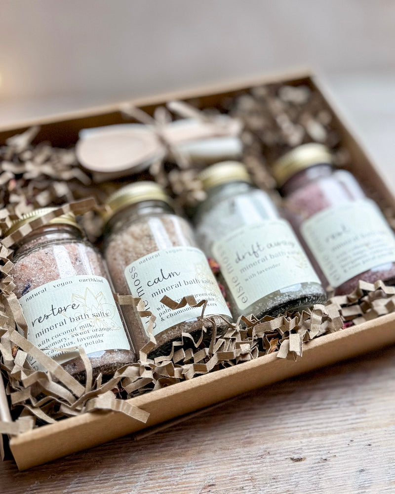 Set of bath salts in small jars with labels in a decorative box.