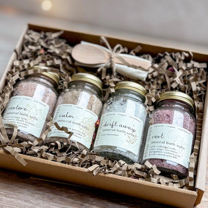 Set of four jars of mineral bath salts in a decorative box with tissue paper.