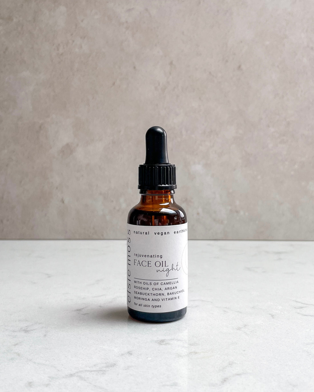 Bottle of face oil with dropper on a light surface and gray background