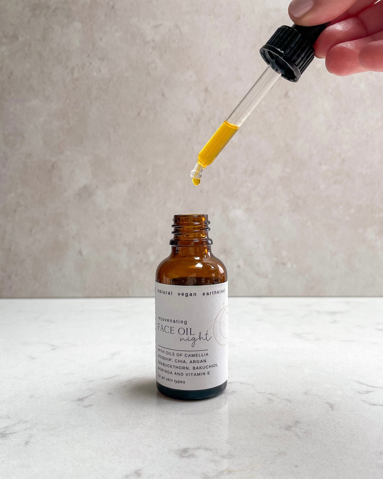 Bottle of face oil with a dropper on a marble surface