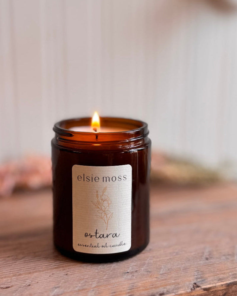 Candle in an amber jar with a label on a wooden surface