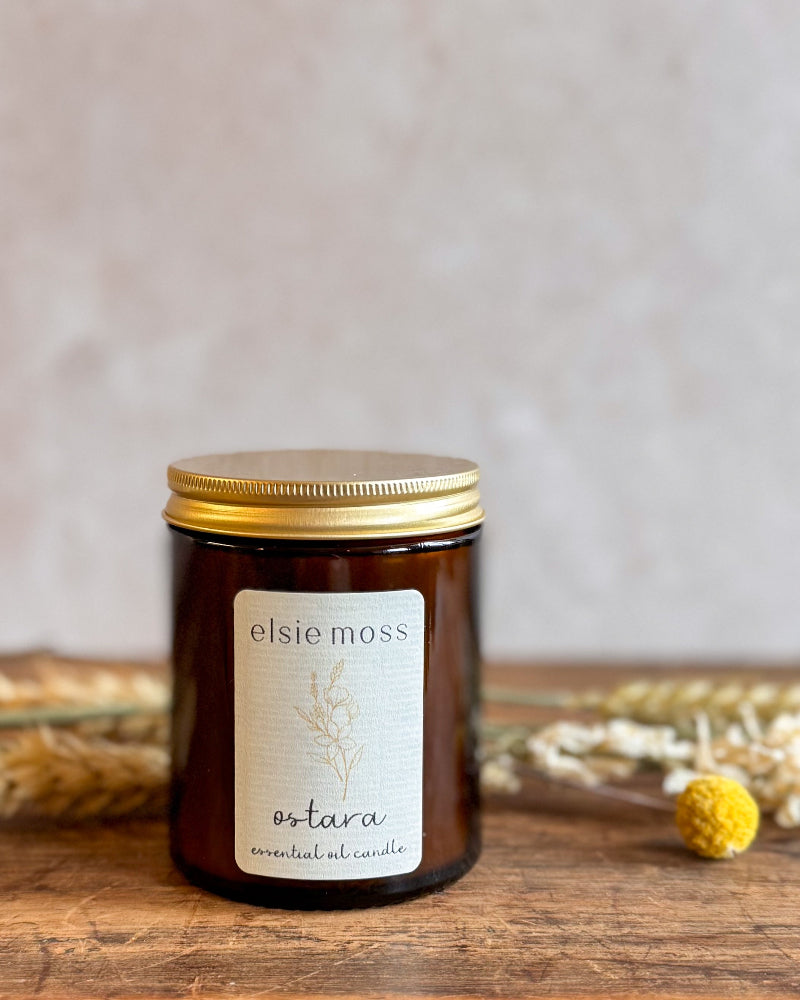 Elsie Moss Ostara candle on a wooden surface with a neutral background