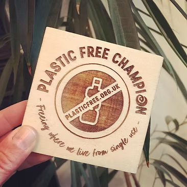 Card with 'Plastic Free Champion' branding held in front of a plant