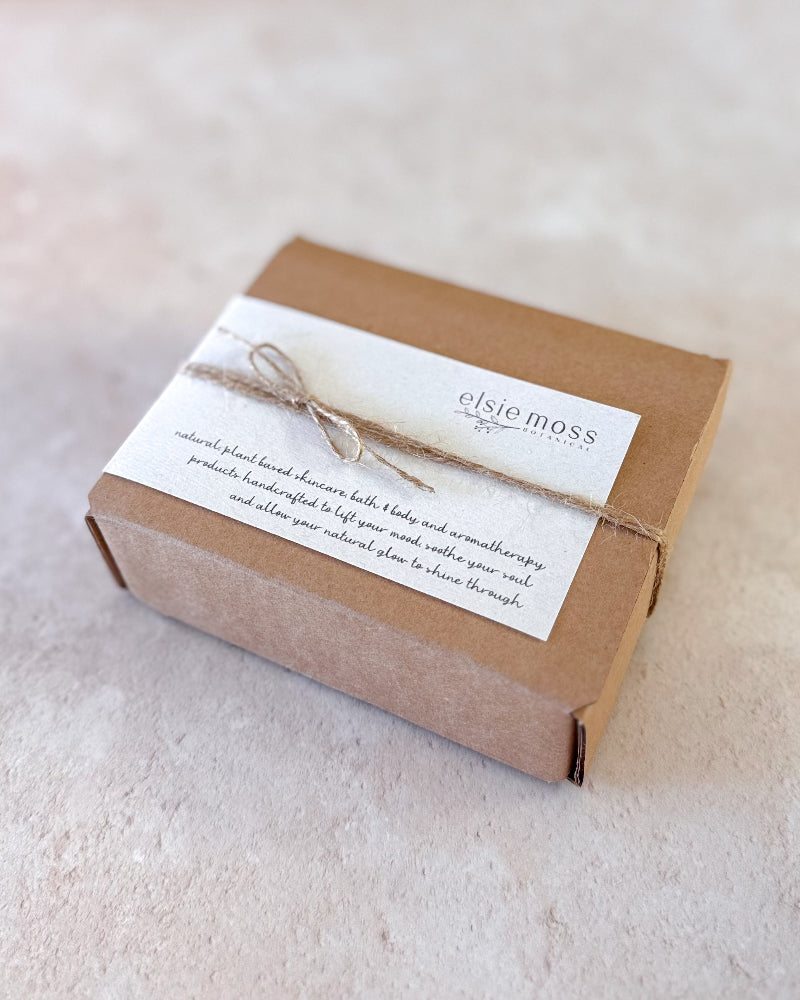 A square kraft paper gift box wrapped with a white paper band tied with twine, featuring the &