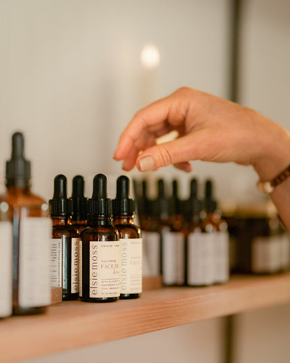 Hand reaching for a bottle on a shelf with skincare products