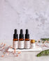 Four dropper bottles with labels on a white surface with a light gray background