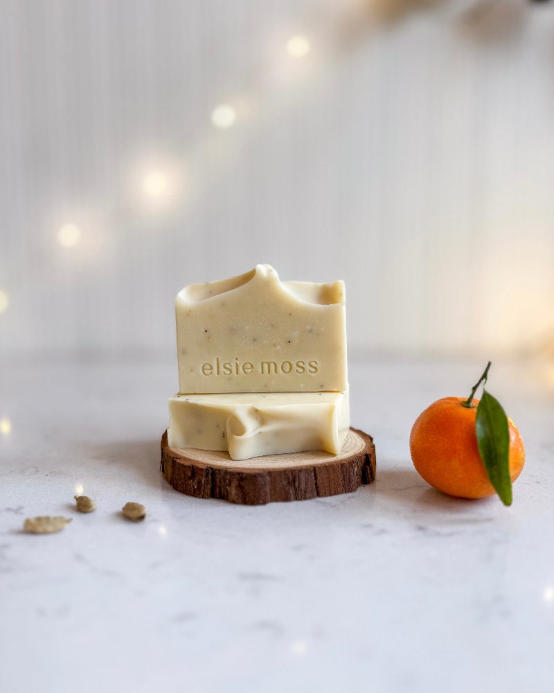 Two bars of soap on a wooden coaster with &